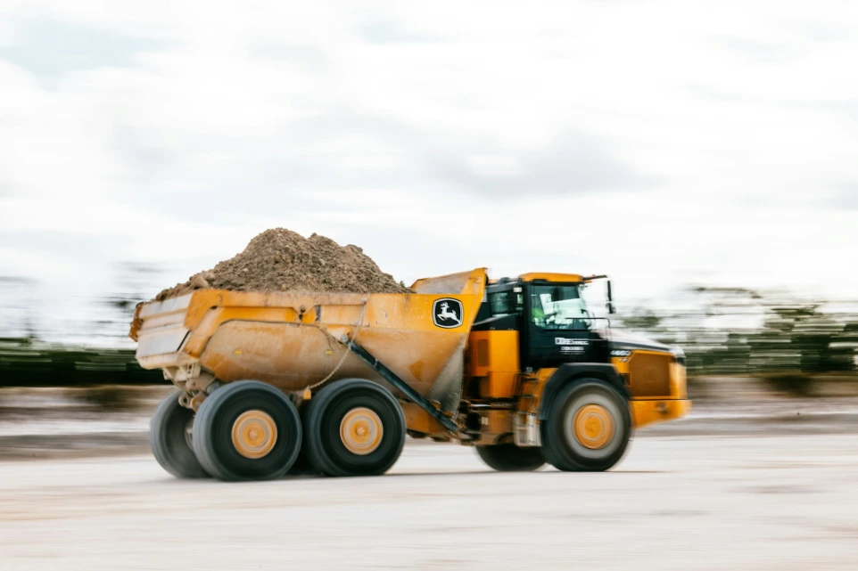 A yellow dump truck is hauling dirt